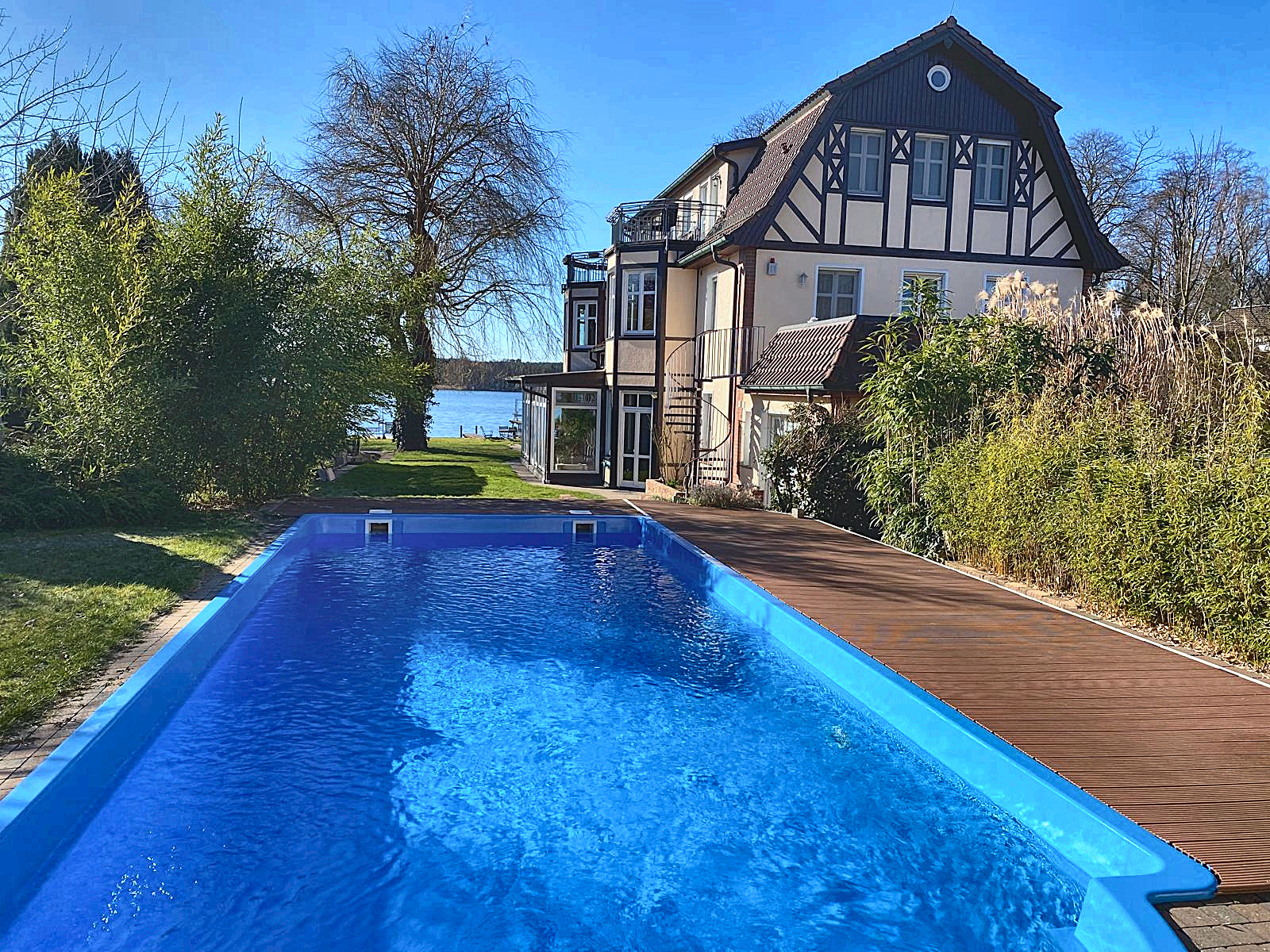 Beheizter Salzwasserpool mit Holzdeck, dahinter die Villa am Krüpelsee