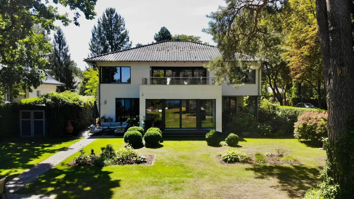 Gartenansicht der Villa in Senzig: weißes, zweigeschossiges Haus mit Walmdach, großen Fenstern und Balkon