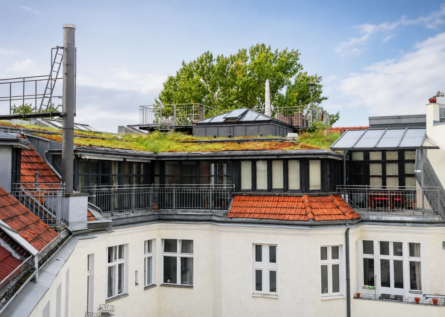 Dachansicht des Berliner Altbaus mit Gründach, Glaselementen und Balkongeländern
