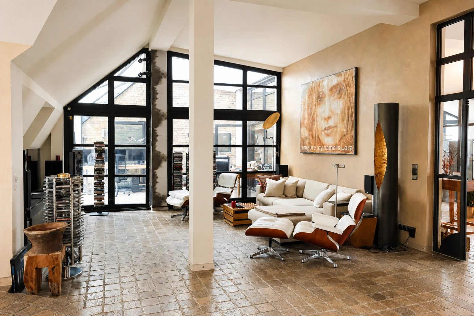 Wohnbereich des Lofts mit hellem Sofa, Designer-Sesseln und Fensterfront