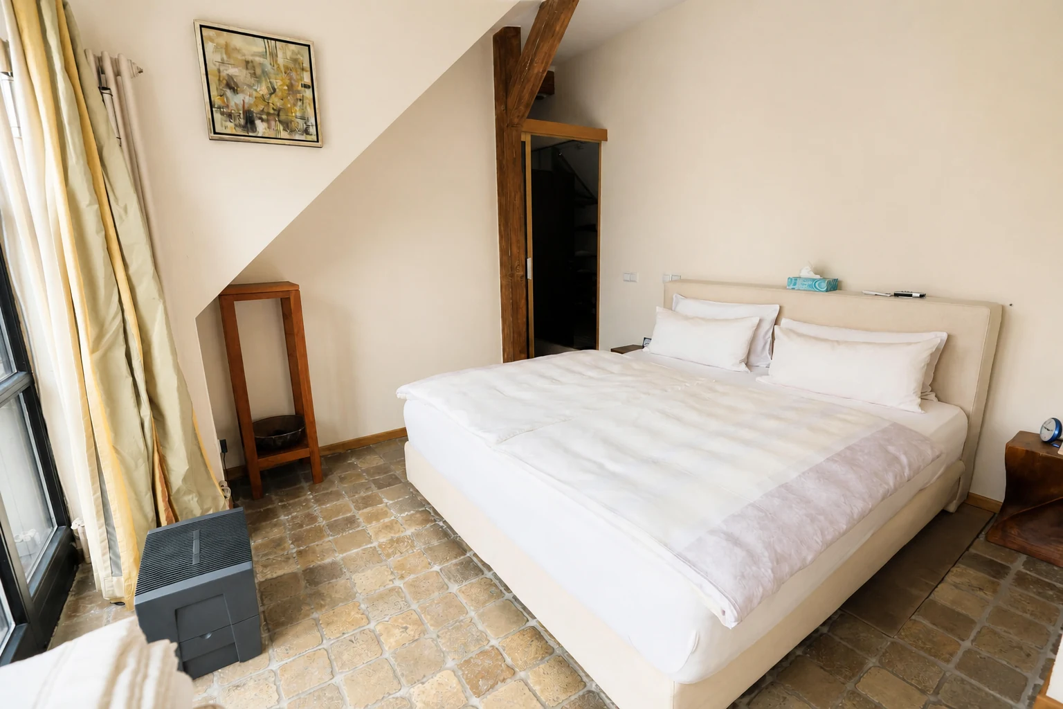 Hauptschlafzimmer mit Doppelbett, Natursteinboden und Holzschräge
