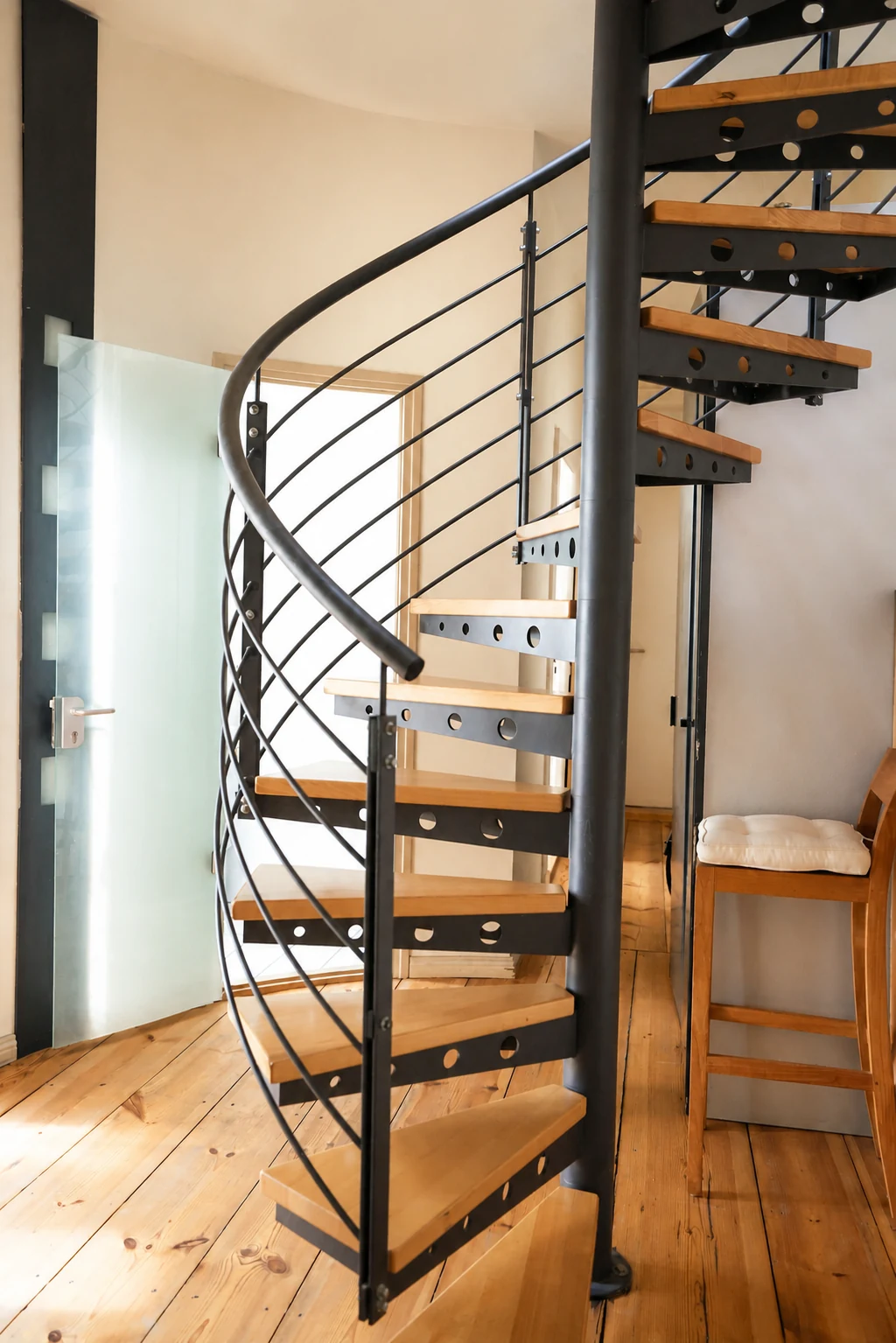 Schwarze Wendeltreppe mit Holzstufen verbindet die beiden Ebenen des Lofts